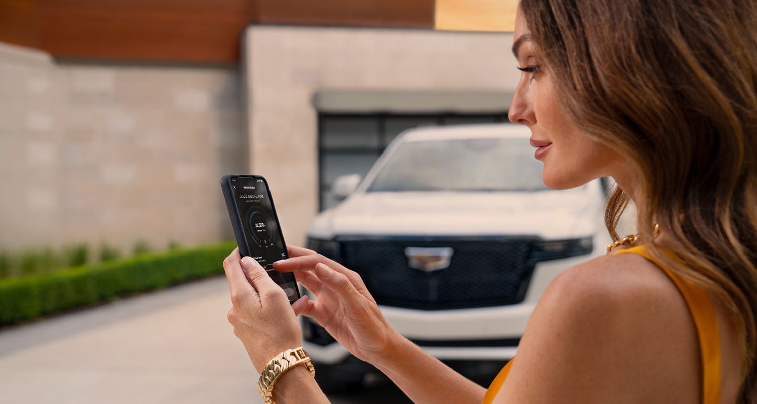 lady checking her mobile with a Cadillac vehicle background | Keller Motors Cadillac in hanford CA