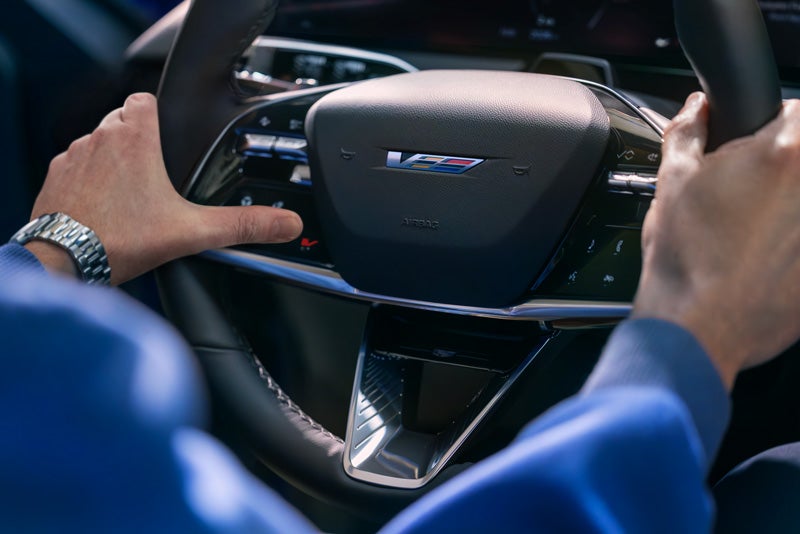 Close-up of a Man About to Press the V-Button on the 2026 OPTIQ-V Steering Wheel | Keller Motors Cadillac in hanford CA